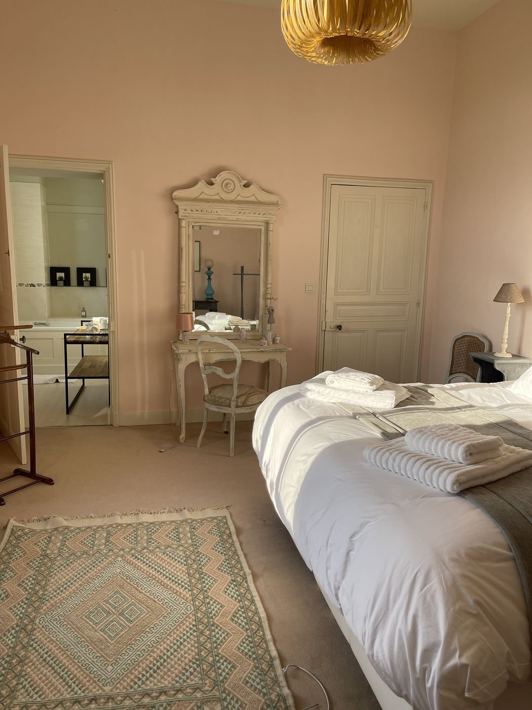 Chambre Gloria : murs rose poudré, coiffeuse ancienne et salle de bains attenante