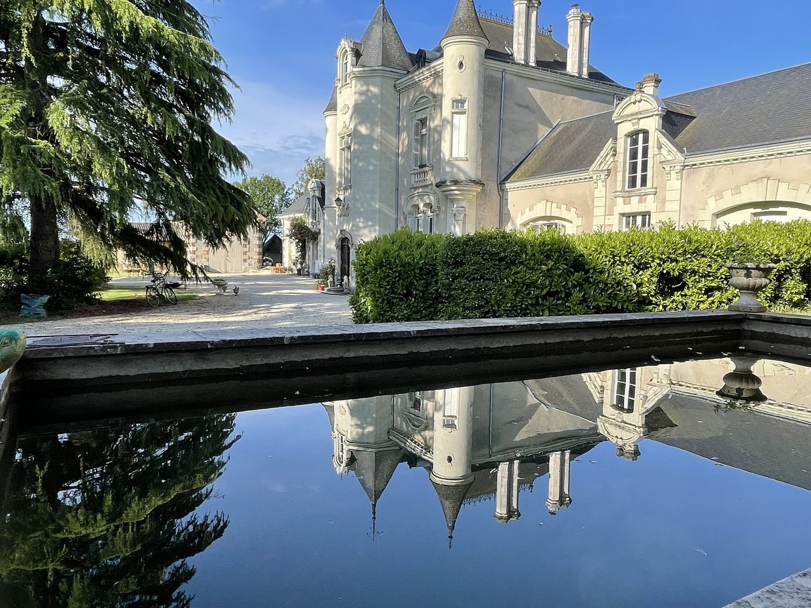 La façade du Château de Leugny et ses tourelles se reflétant dans le bassin