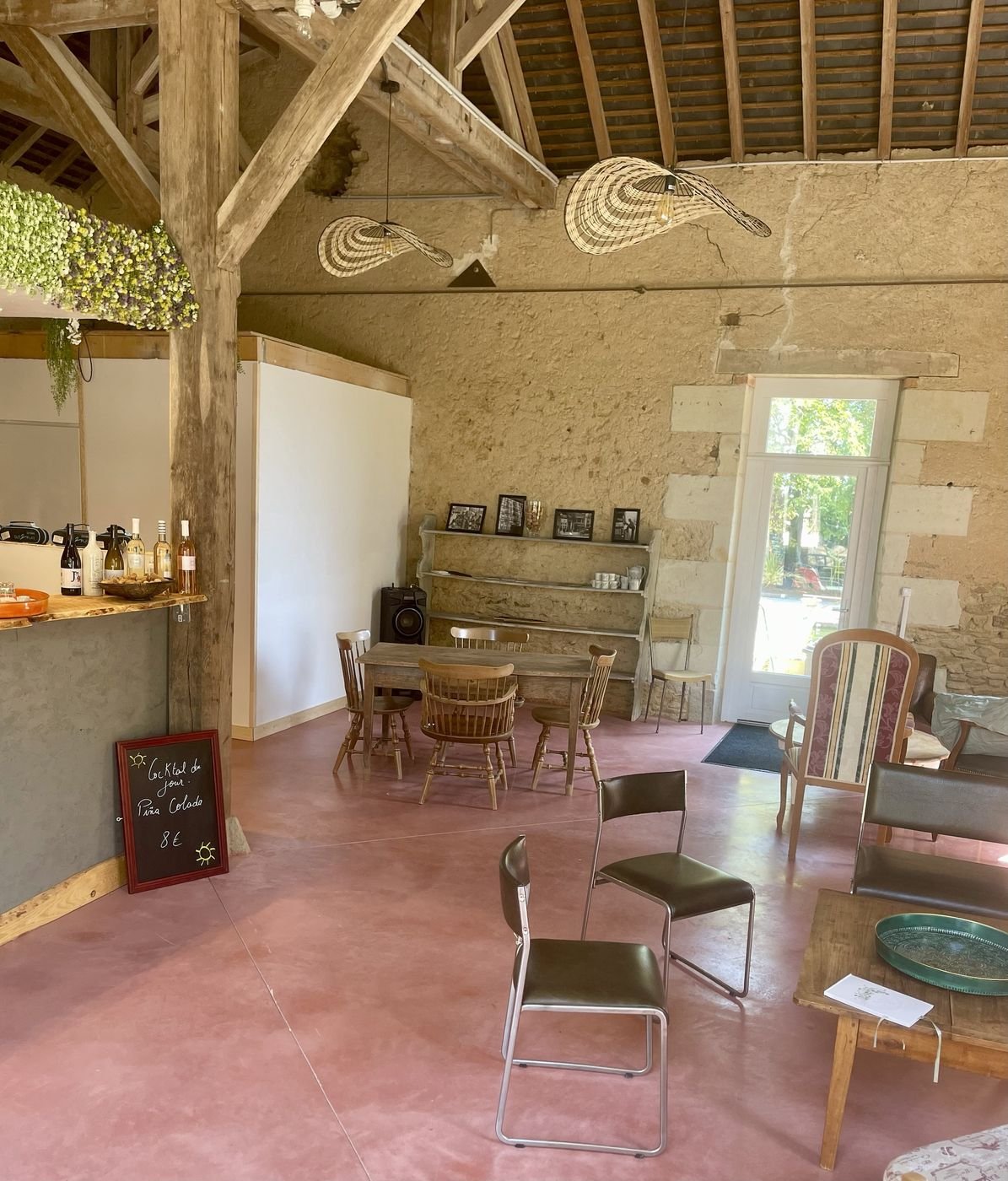 La salle du Garage : charpente apparente, murs en pierre, bar et tables anciennes